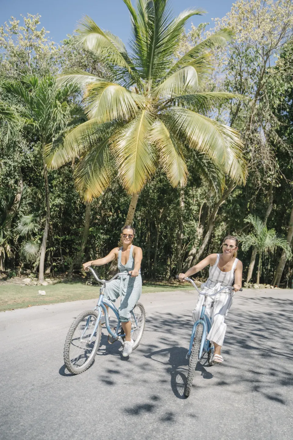 Two guests biking on a palm-lined path at Generations Riviera Maya.
