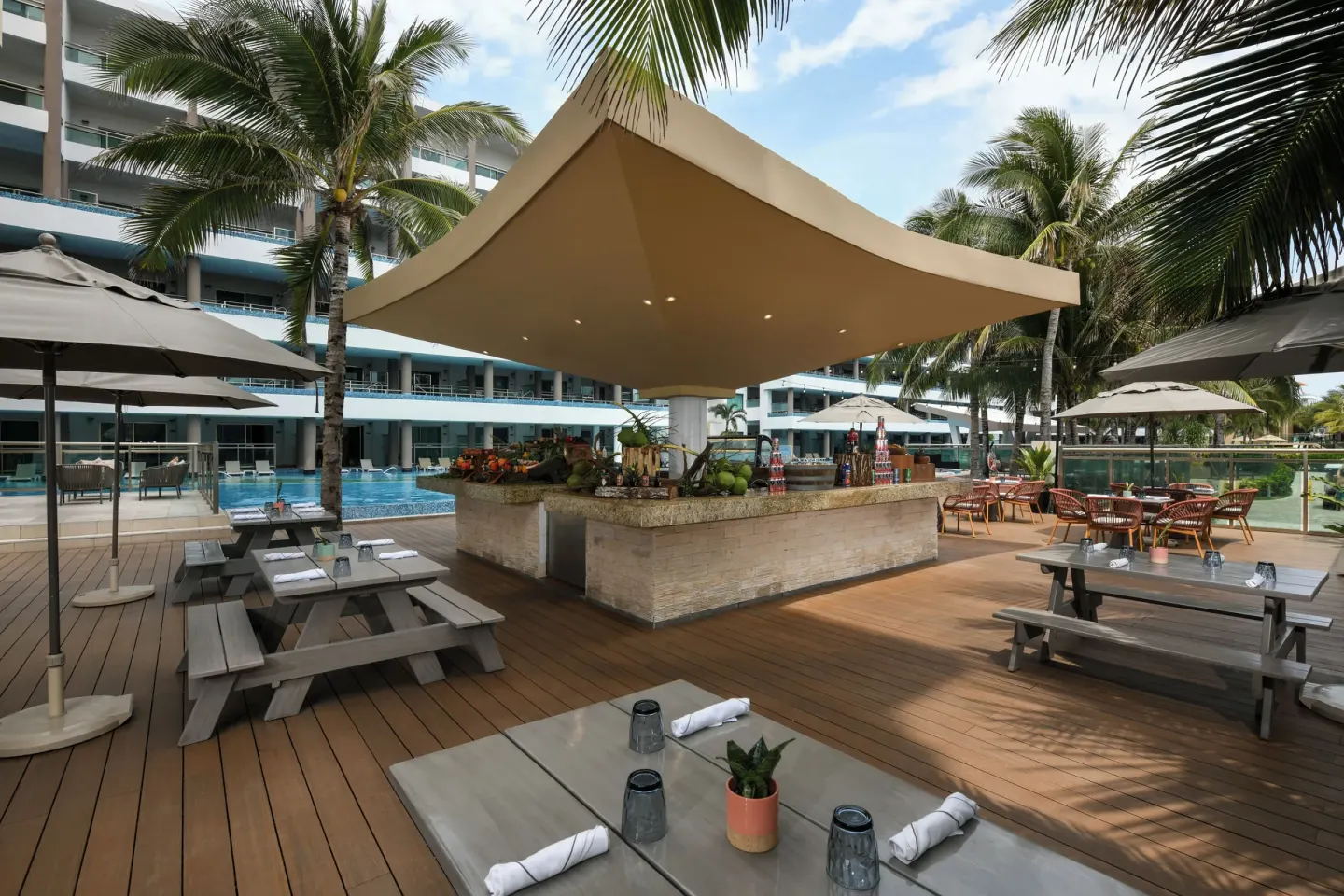 Poolside deck with shaded bar and picnic tables at Generations Riviera Maya.