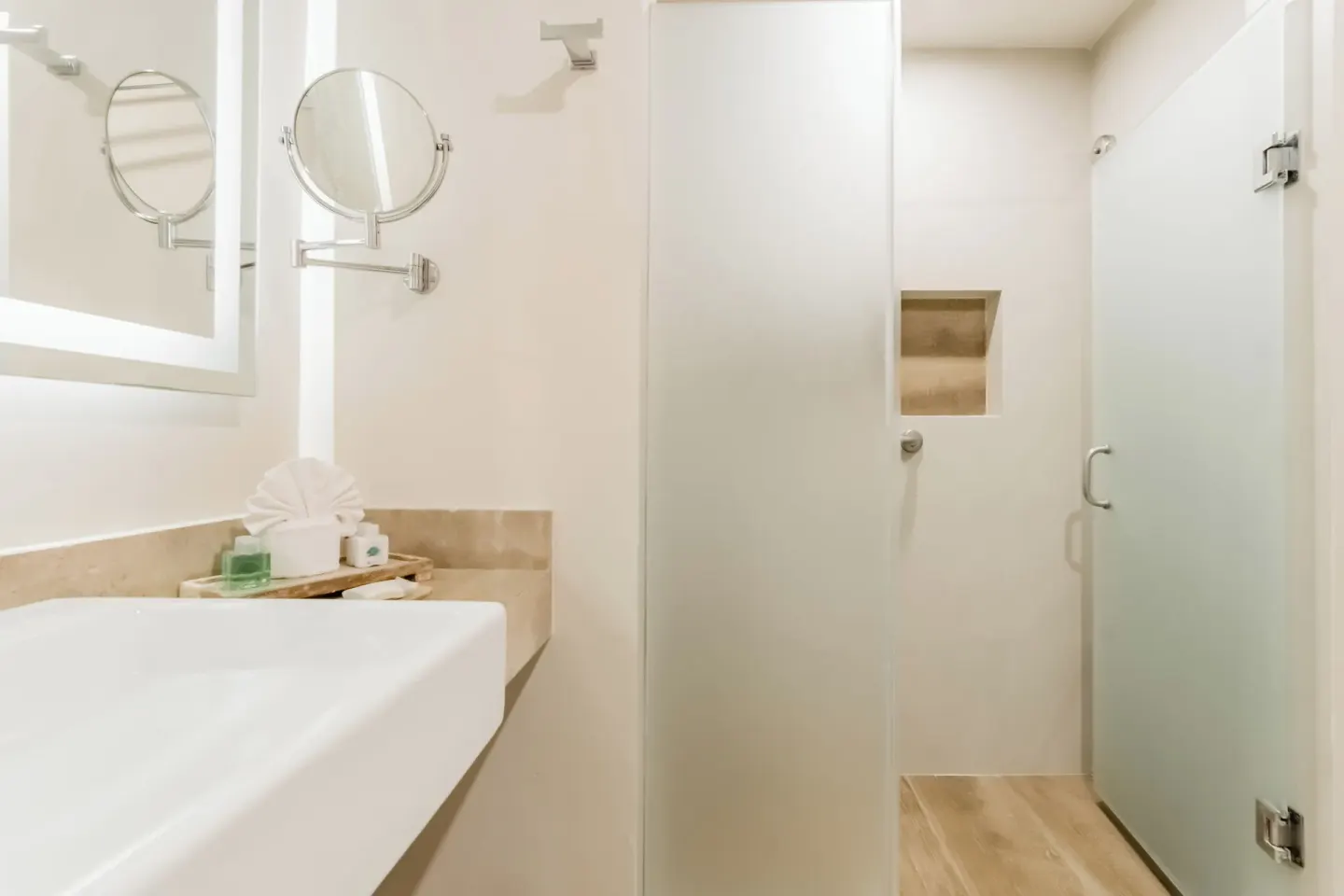 Guest bathroom with sink, mirrors, and glass shower at GR Solaris Cancun & Spa.