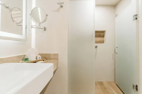 Guest bathroom with sink, mirrors, and glass shower at GR Solaris Cancun & Spa.