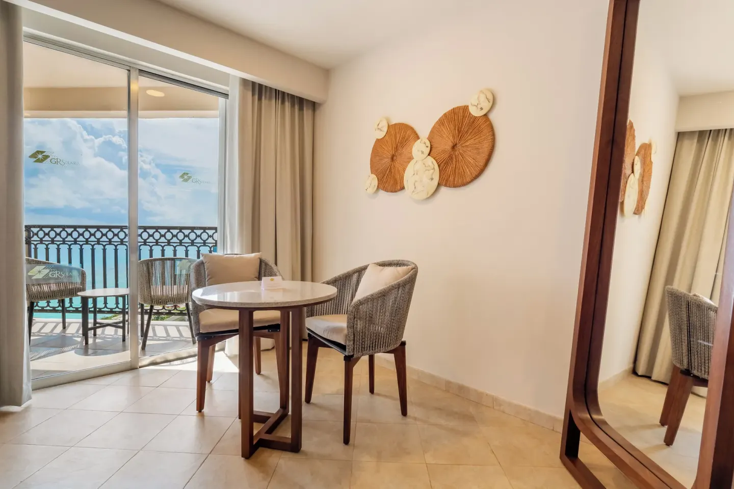 Guest room sitting area with balcony view at GR Solaris Cancun & Spa.