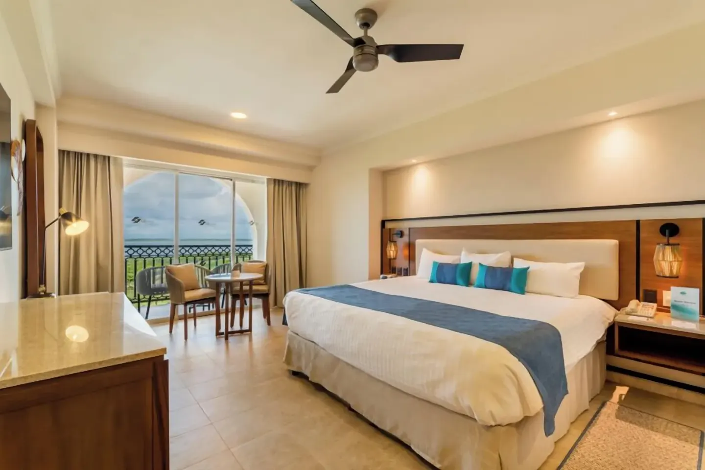 King bed room with balcony seating and ocean view at GR Solaris Cancun & Spa.