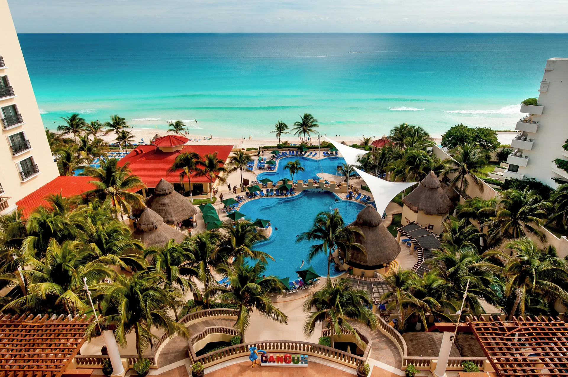 Aerial view of the pools, palms, beach, and Caribbean Sea at GR Solaris Cancun & Spa.