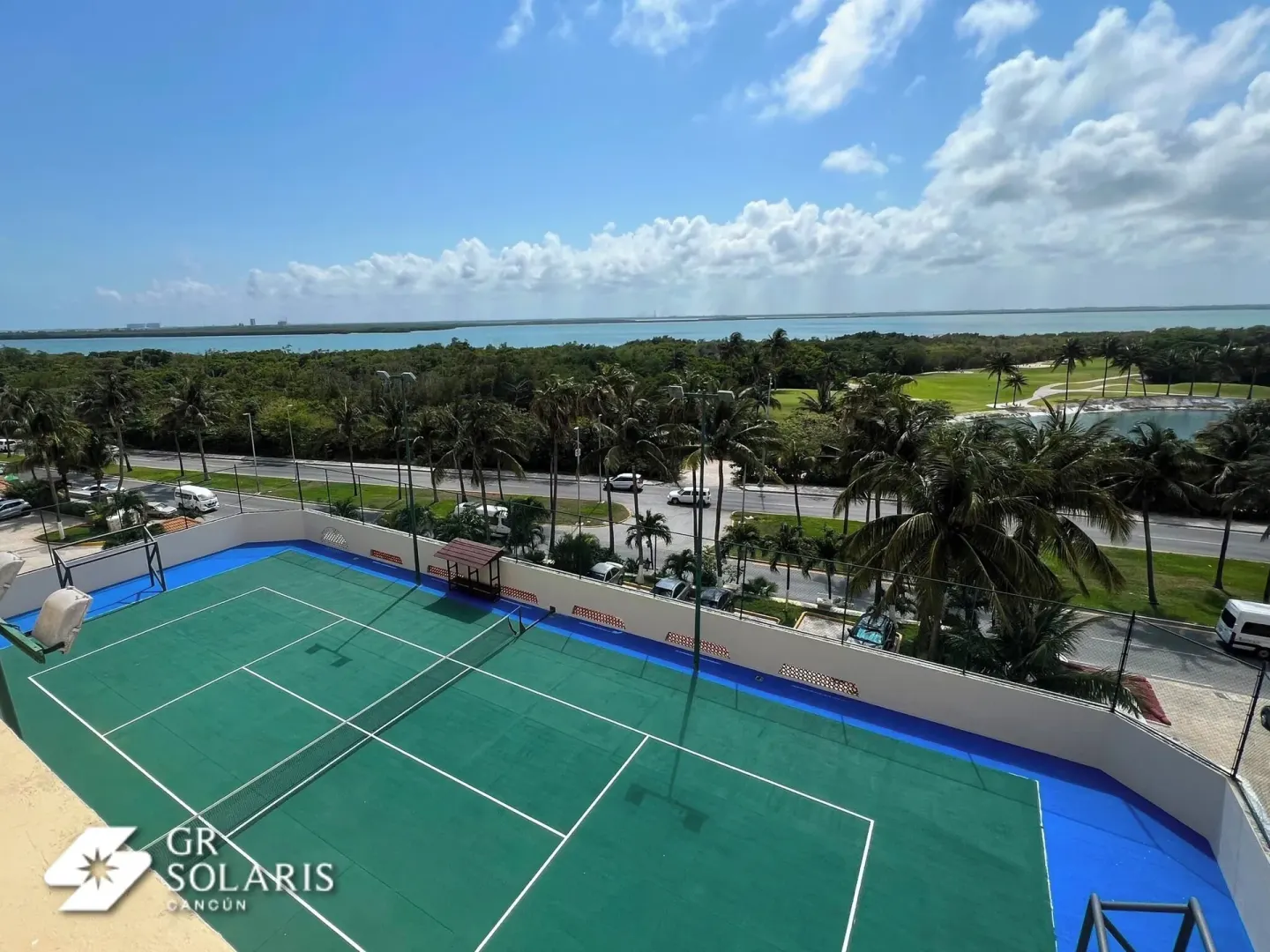 Tennis courts overlooking palms, road, and lagoon at GR Solaris Cancun & Spa.