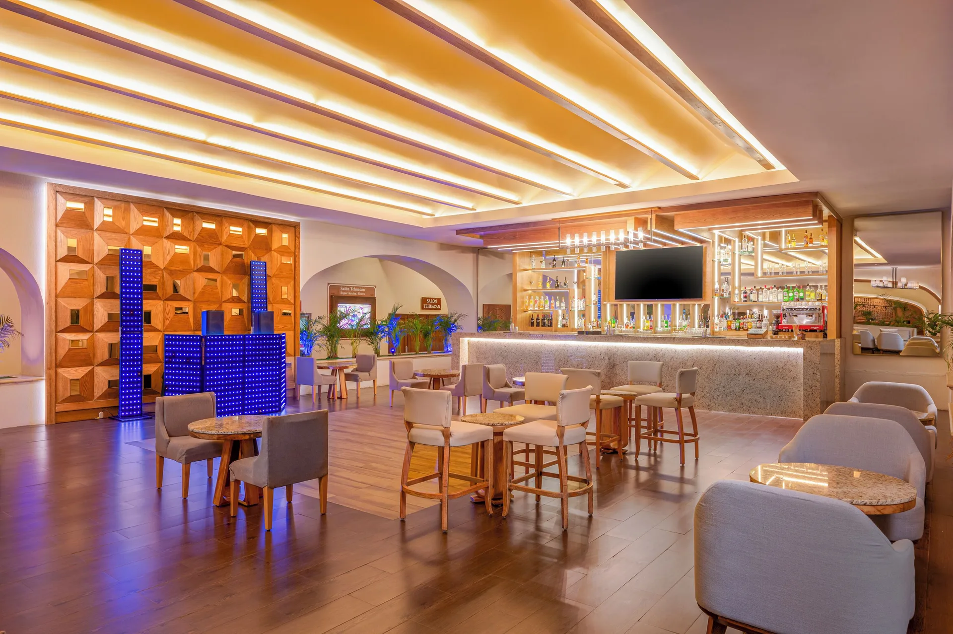 Lobby bar with illuminated counter and lounge seating at GR Solaris Cancun & Spa.