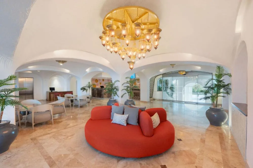 Lobby seating area with red sofa and chandelier at GR Solaris Caribe.