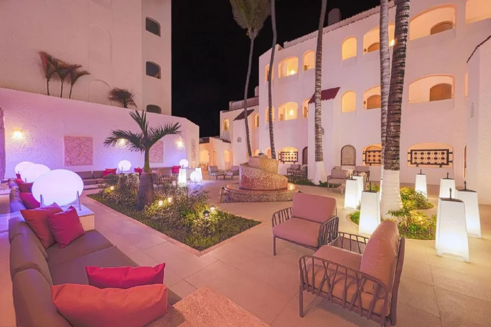 Night courtyard lounge with glowing lights and palm trees at GR Solaris Caribe.