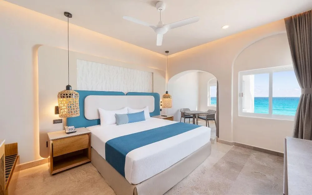 Guest room with king bed and ocean-view window at GR Solaris Caribe.