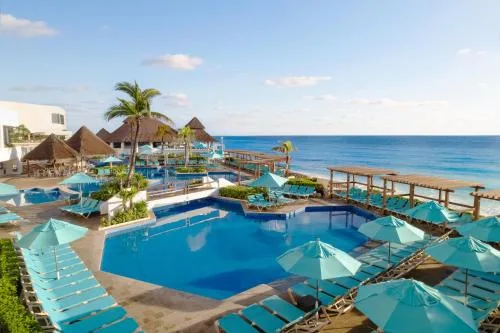 Oceanfront pool deck with turquoise umbrellas at GR Solaris Caribe.