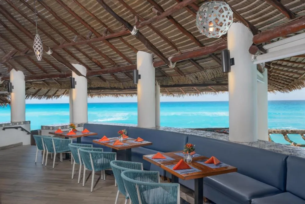 Open-air oceanfront restaurant terrace with set tables at GR Solaris Caribe.
