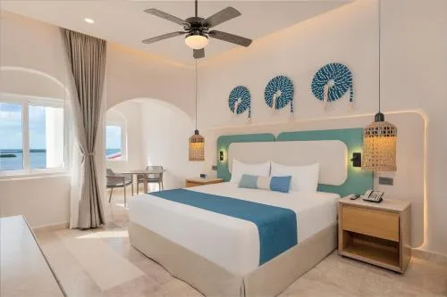 Oceanfront Suite with Private Plunge Pool at GR Solaris Caribe featuring a king bed, modern pendant lighting, and direct ocean views in Cancun's Hotel Zone.