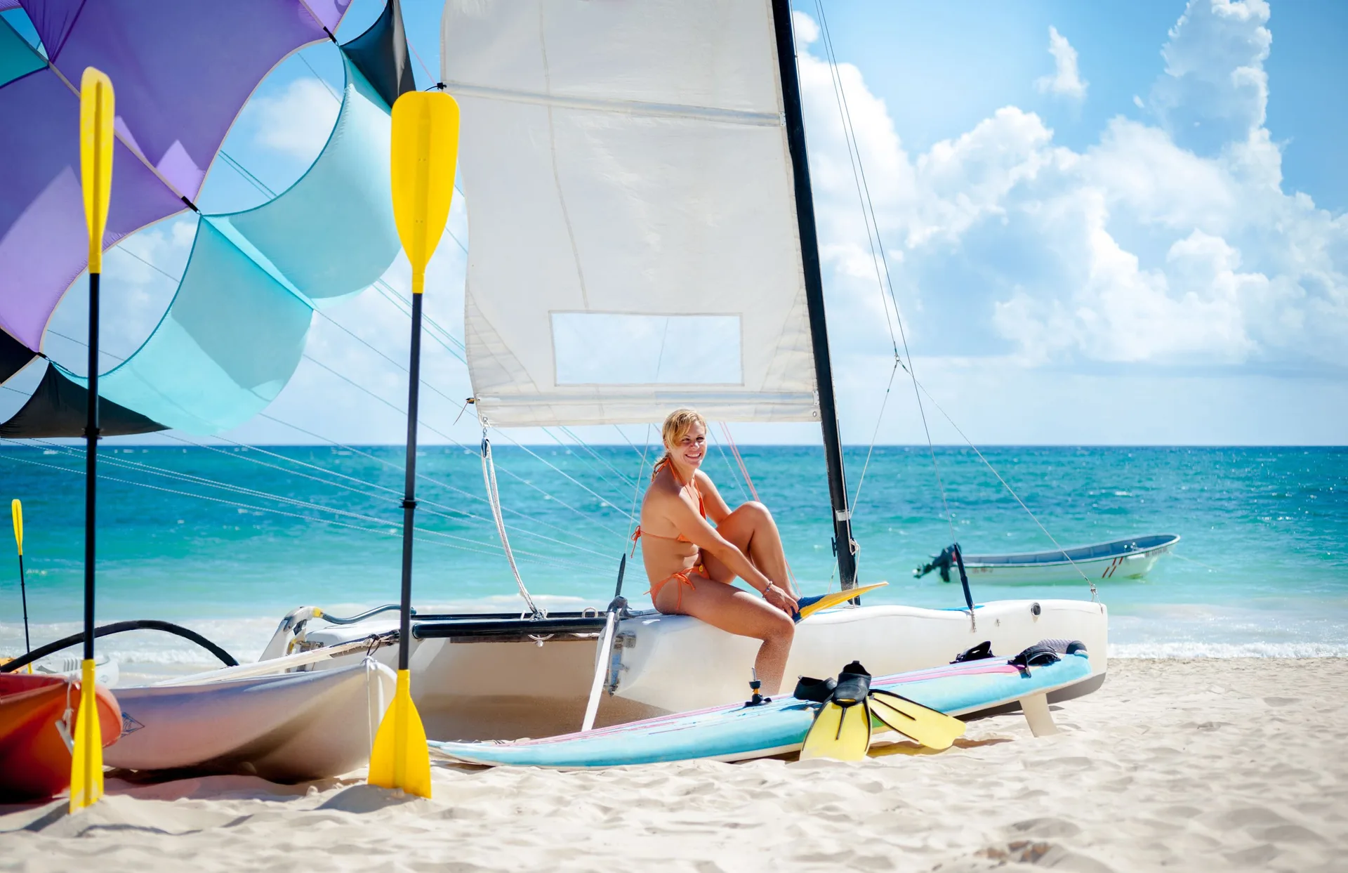 A guest sits on a beach catamaran by turquoise water at Grand Bavaro Princess.