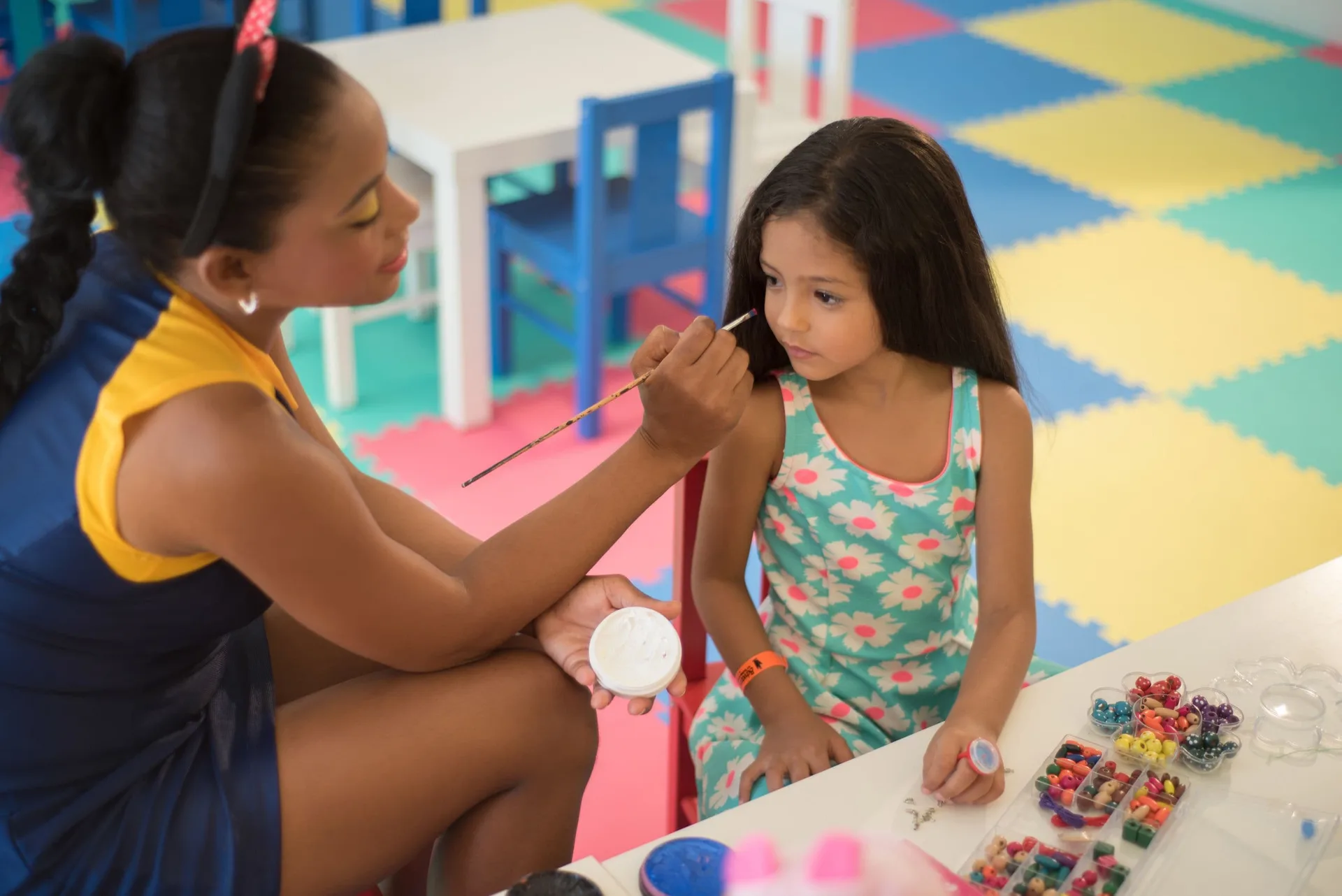 A child receives face painting beside craft supplies at Grand Bavaro Princess.