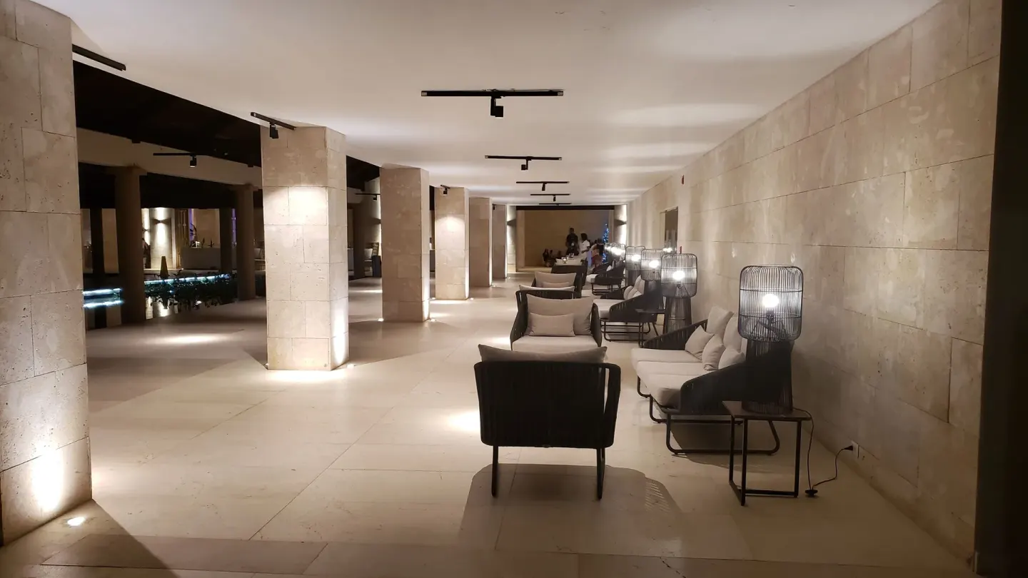 Covered lobby lounge corridor with armchairs and lamps at Grand Bavaro Princess.