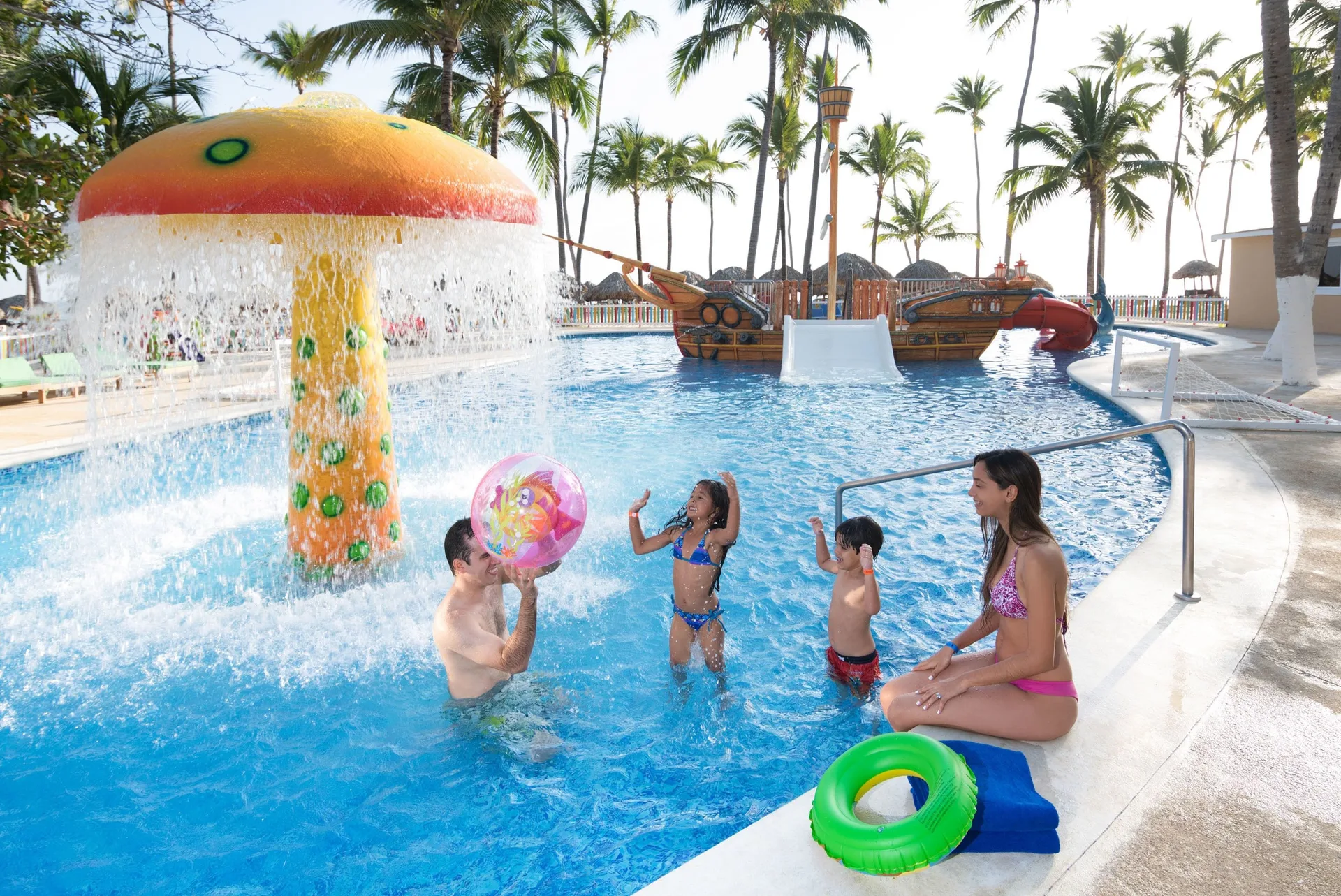 Family playing in the children's pool near the mushroom fountain at Grand Bavaro Princess.