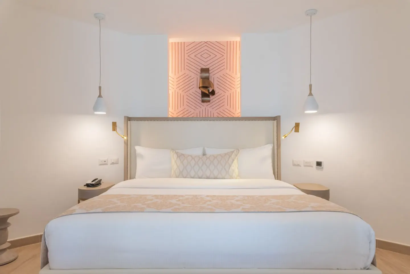 King bed with pendant lights and a geometric wall panel in a guest room at Grand Bavaro Princess.