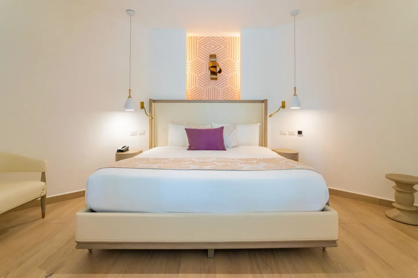 White king bed with purple accent pillow in a guest room at Grand Bavaro Princess.