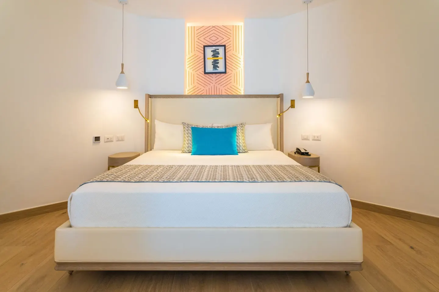 King bed with turquoise accent pillow and pendant lights at Grand Bavaro Princess.
