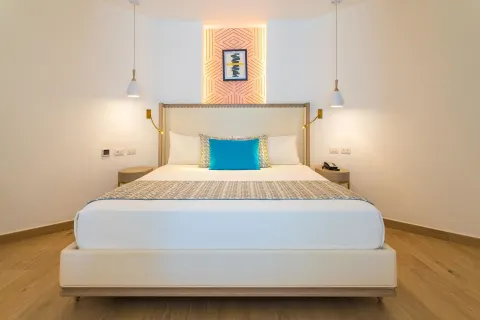 King bed with turquoise accent pillow and pendant lights at Grand Bavaro Princess.