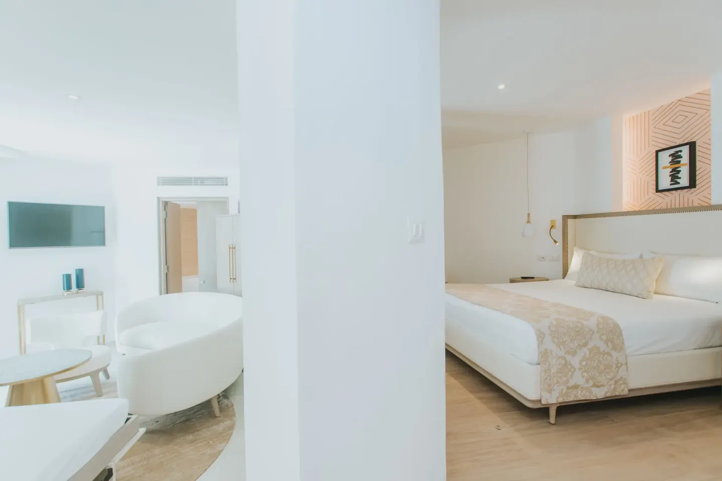 White guest suite with king bed and sitting area at Grand Bavaro Princess.