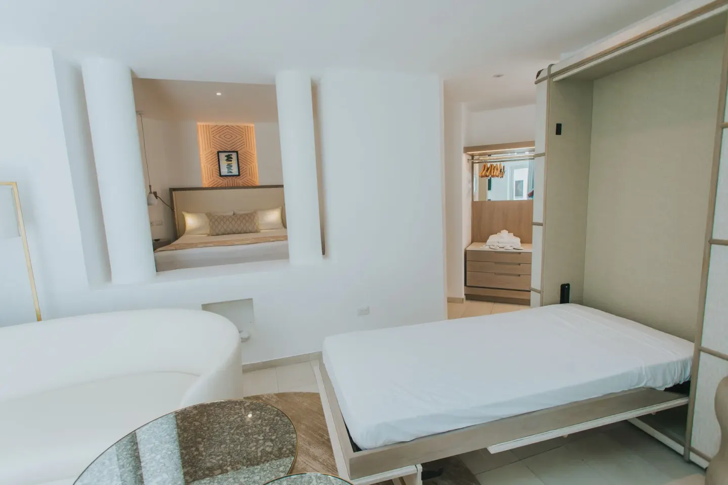 Guest suite with Murphy-style bed, round seating, and bedroom beyond at Grand Bavaro Princess.