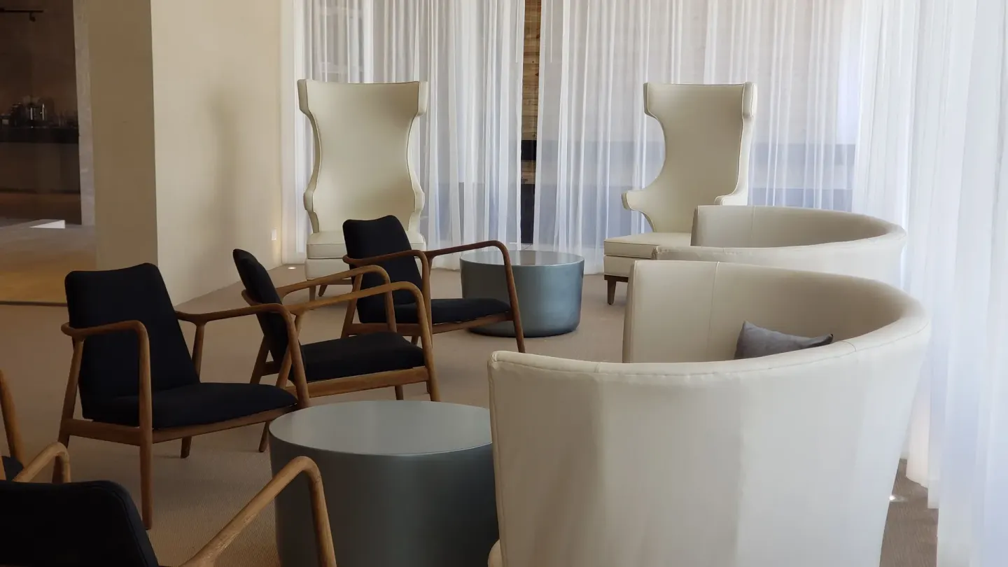 Indoor lounge seating with sheer curtains and high-back chairs at Grand Bavaro Princess.