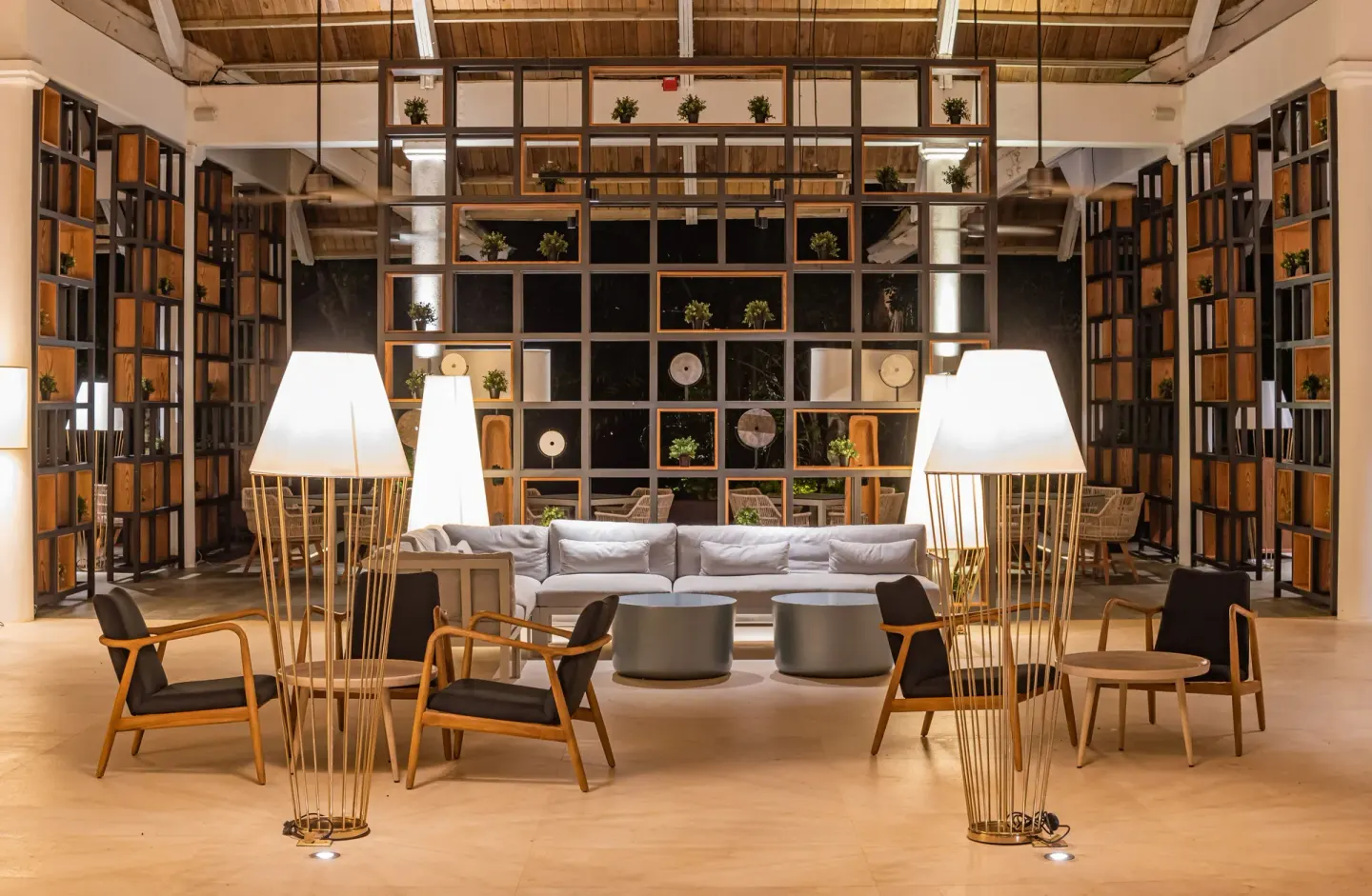 Modern lobby lounge with sofas, lamps, and open shelving at Grand Bavaro Princess.
