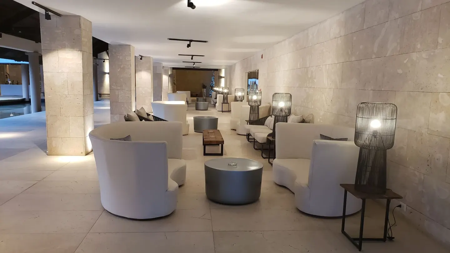 Modern lobby seating with curved white chairs and lit floor lamps at Grand Bavaro Princess.