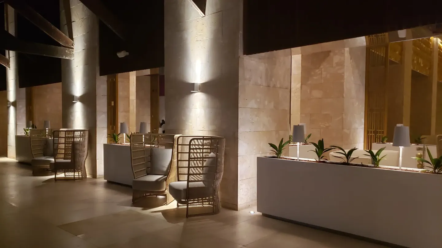 Nighttime covered lobby terrace with planters and lounge chairs at Grand Bavaro Princess.