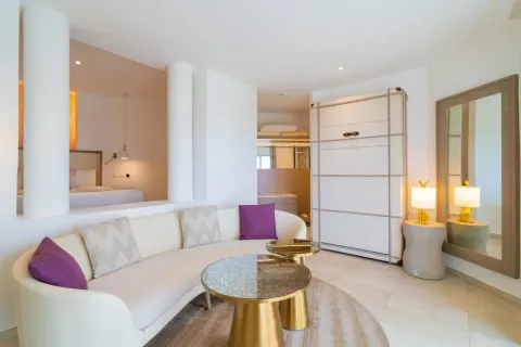 Curved white sofa and bedroom area in a suite at Grand Bavaro Princess.