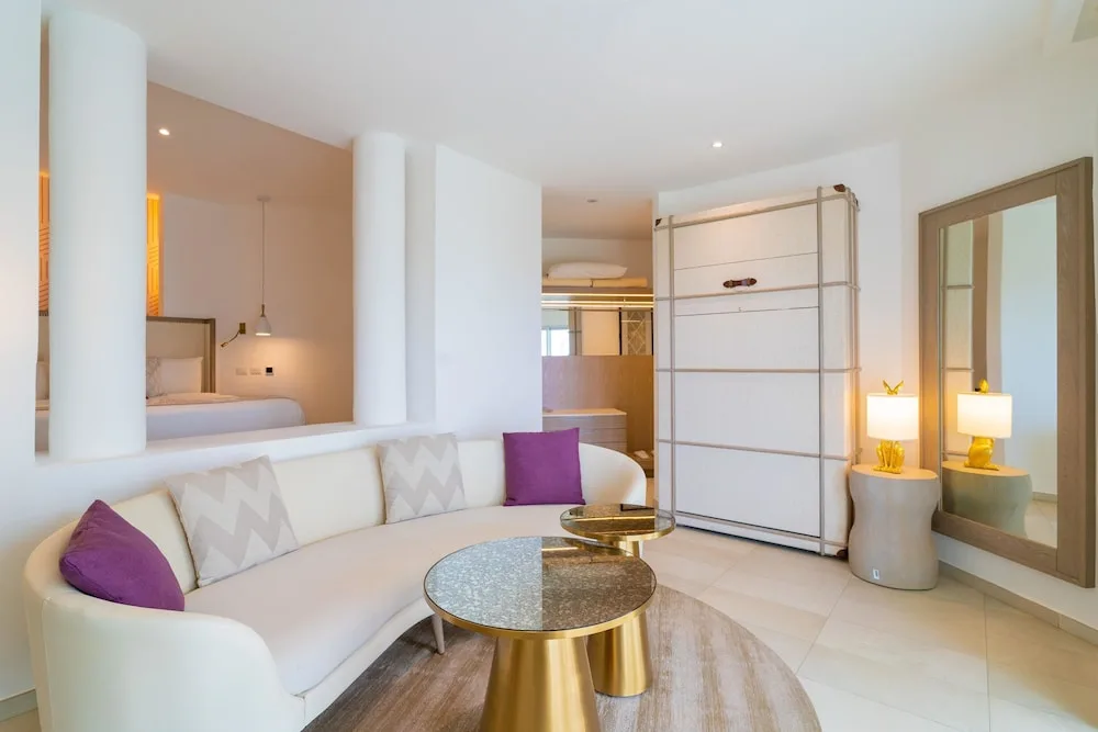 Curved white sofa and bedroom area in a suite at Grand Bavaro Princess.