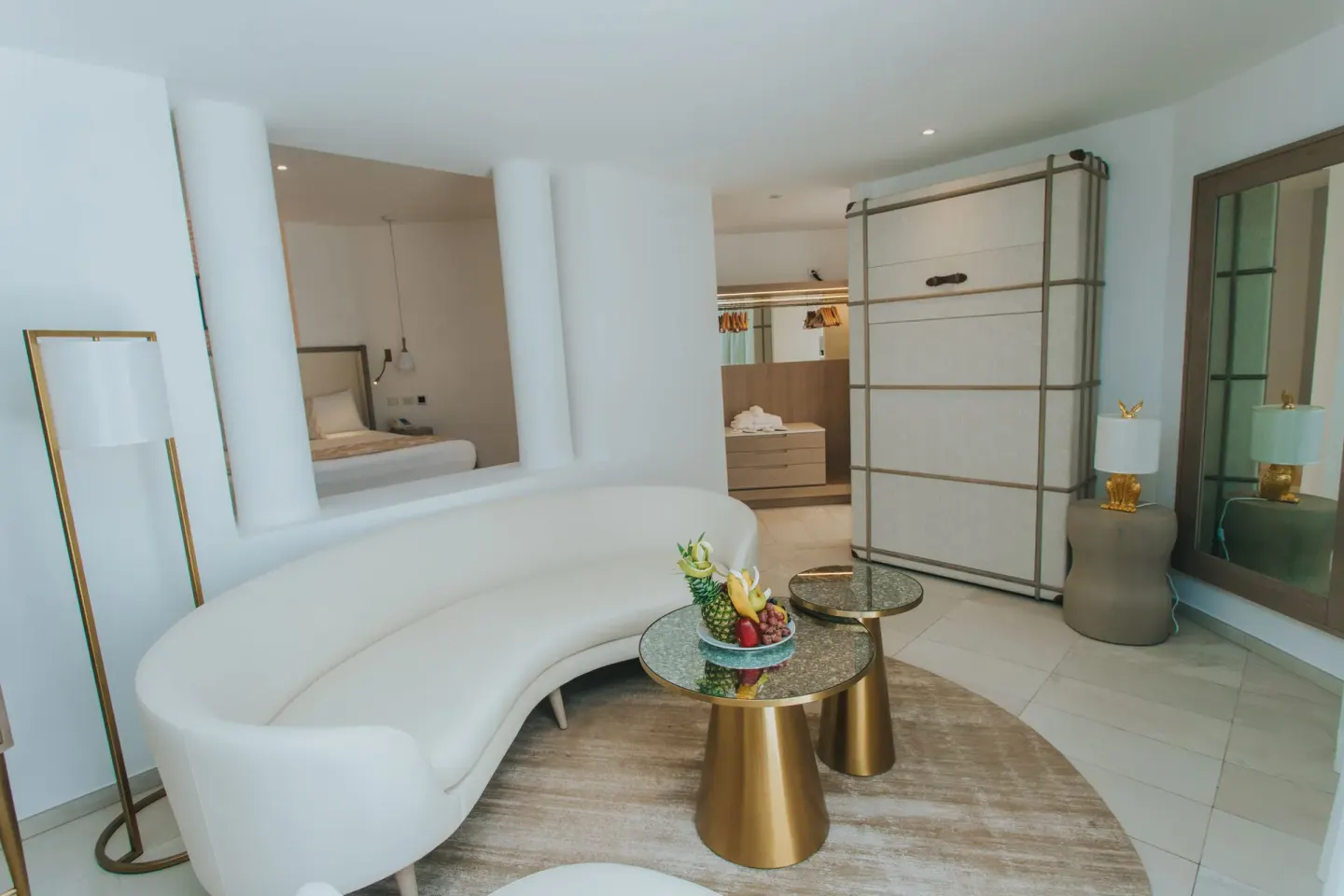 Curved sofa, fruit plate, and dressing area in a suite at Grand Bavaro Princess.