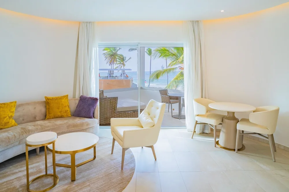 Bright suite living area with balcony and ocean view at Grand Bavaro Princess.