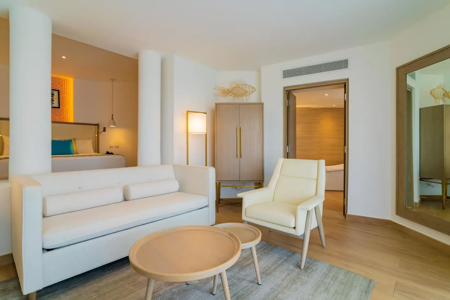 Suite lounge with white sofa and bedroom alcove at Grand Bavaro Princess.