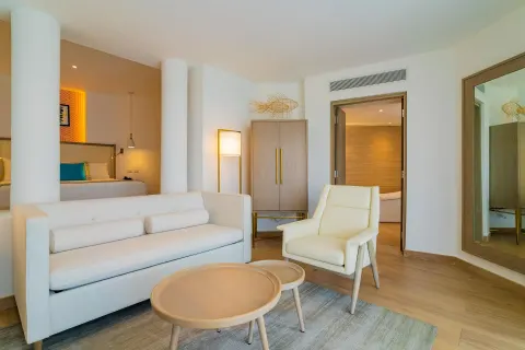 Suite lounge with white sofa and bedroom alcove at Grand Bavaro Princess.
