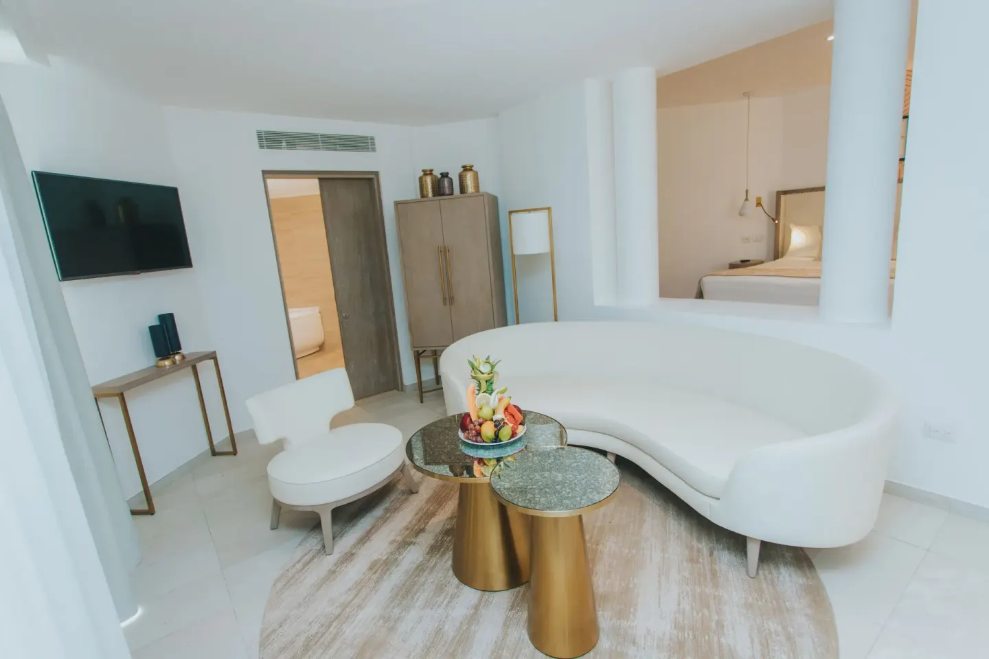 Curved white sofa and lounge area in a suite at Grand Bavaro Princess.