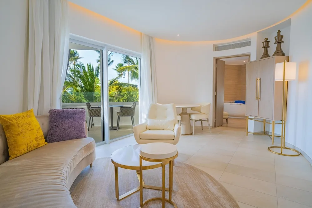 Suite lounge with balcony, palms, and bedroom doorway at Grand Bavaro Princess.