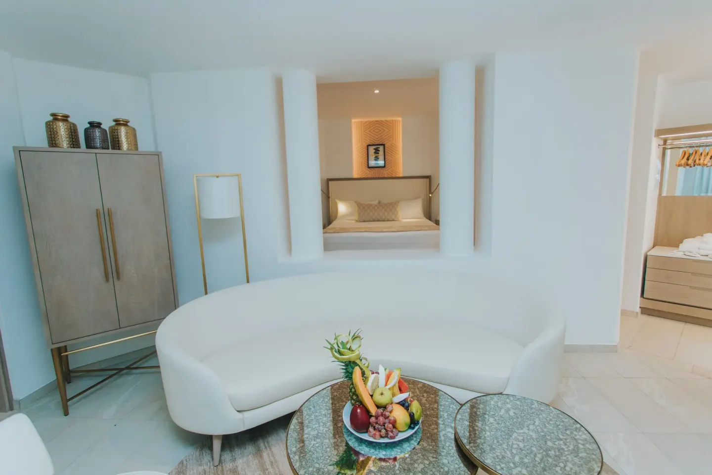 Suite sitting area with curved sofa and bed visible beyond at Grand Bavaro Princess.