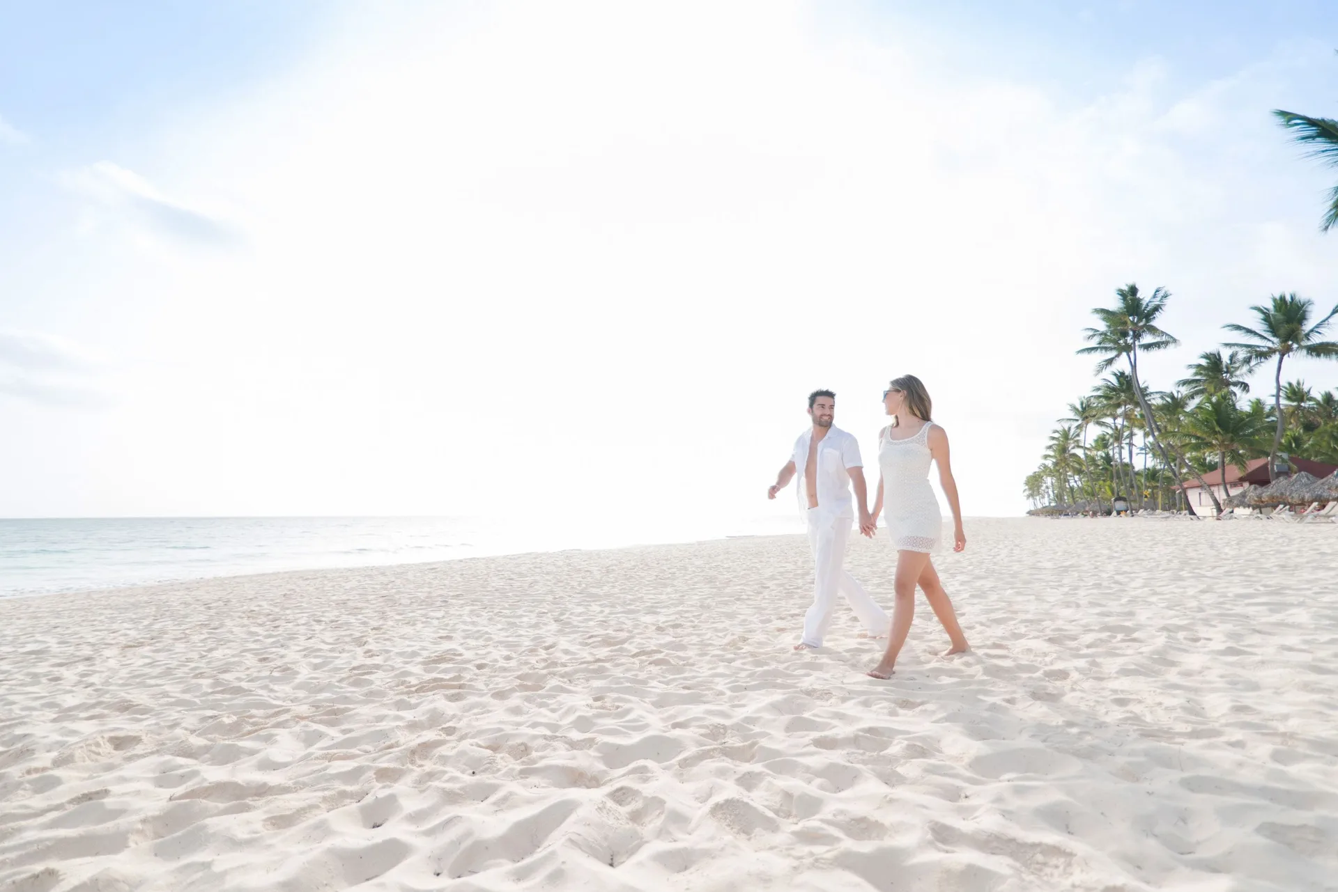 Couple walking on the white-sand beach at Grand Bavaro Princess.