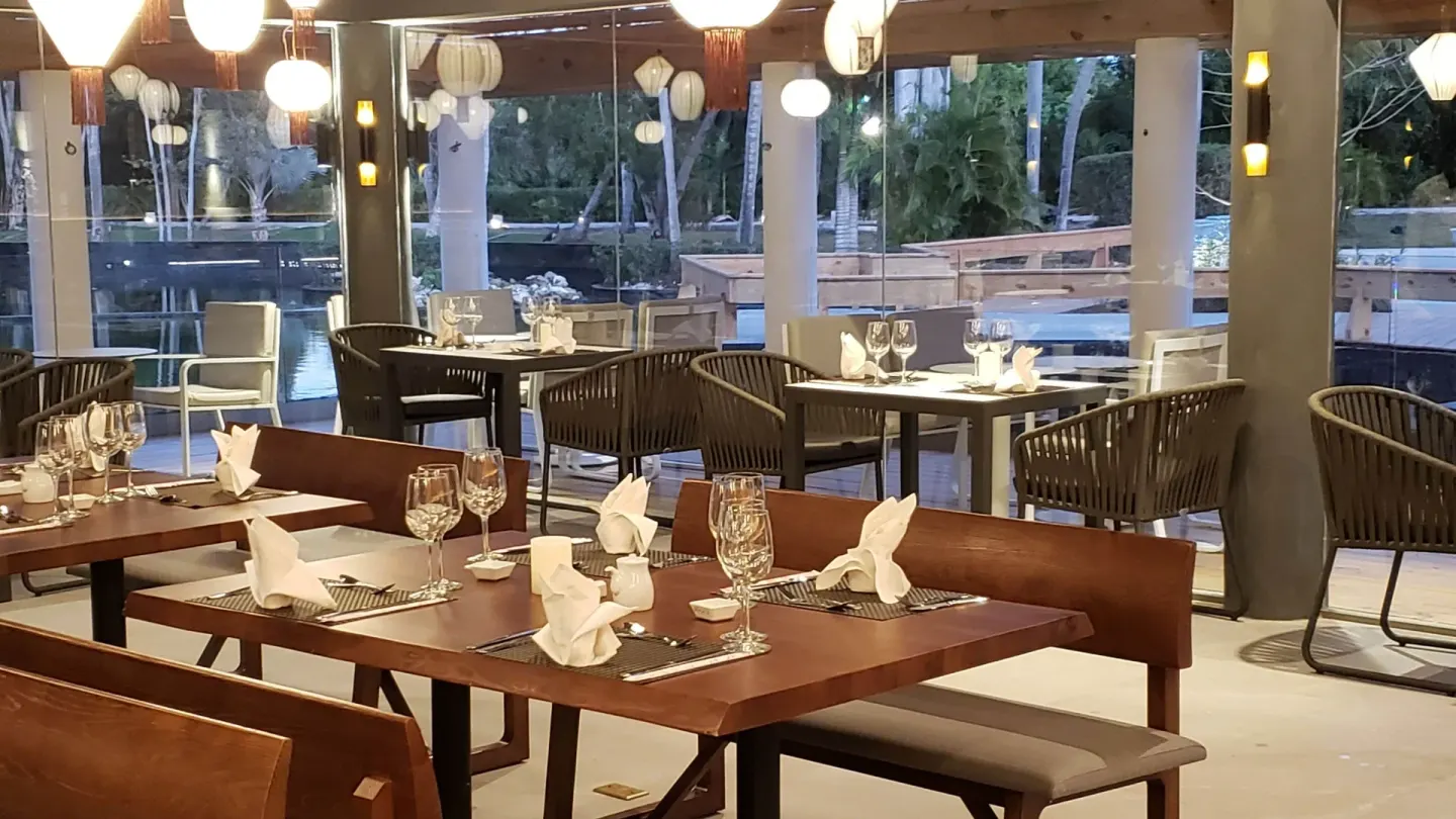 Lagoon-side dining tables set with glassware and napkins at Grand Bavaro Princess.