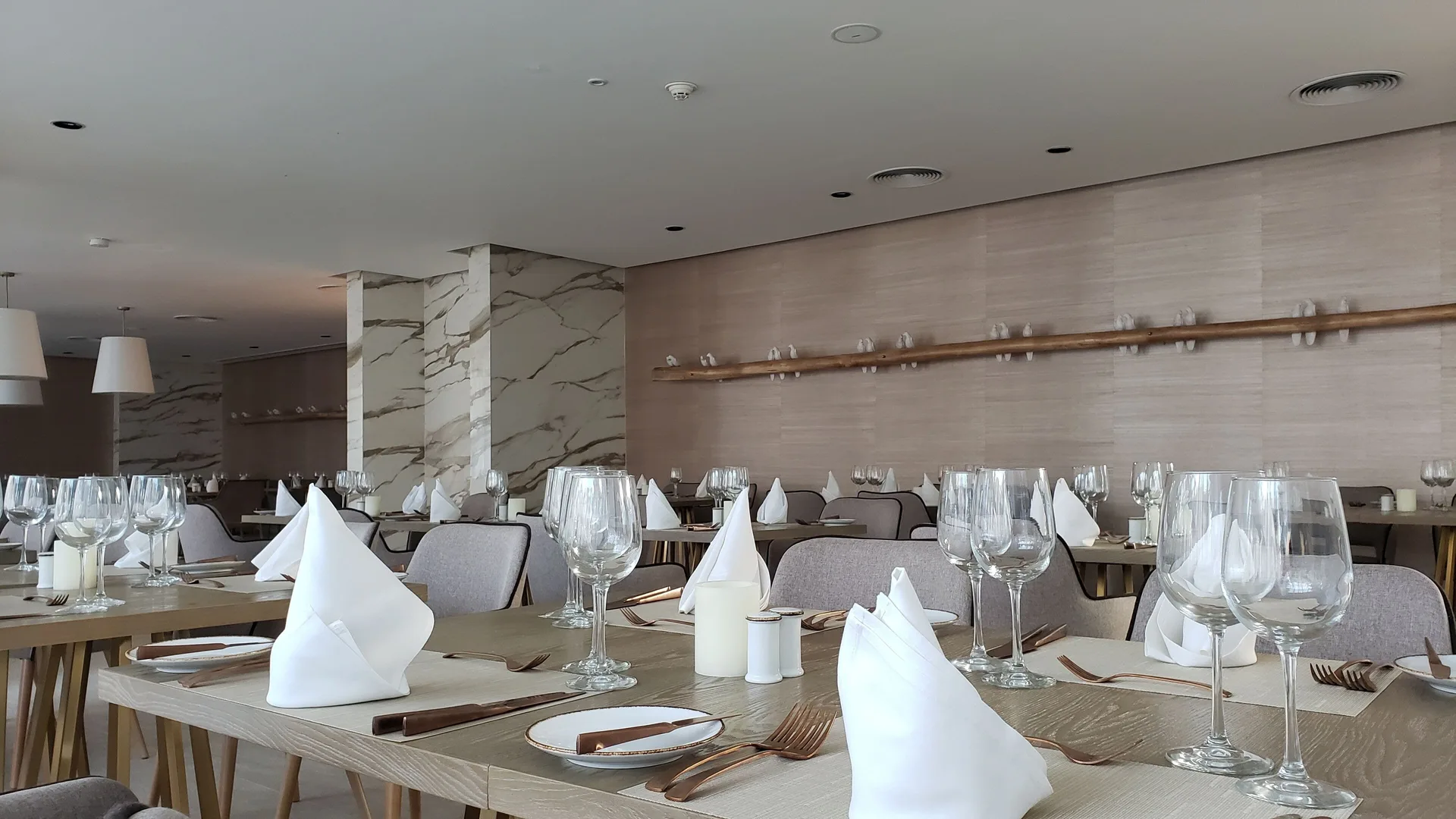 Neutral-toned restaurant tables set with glassware at Grand Bavaro Princess.