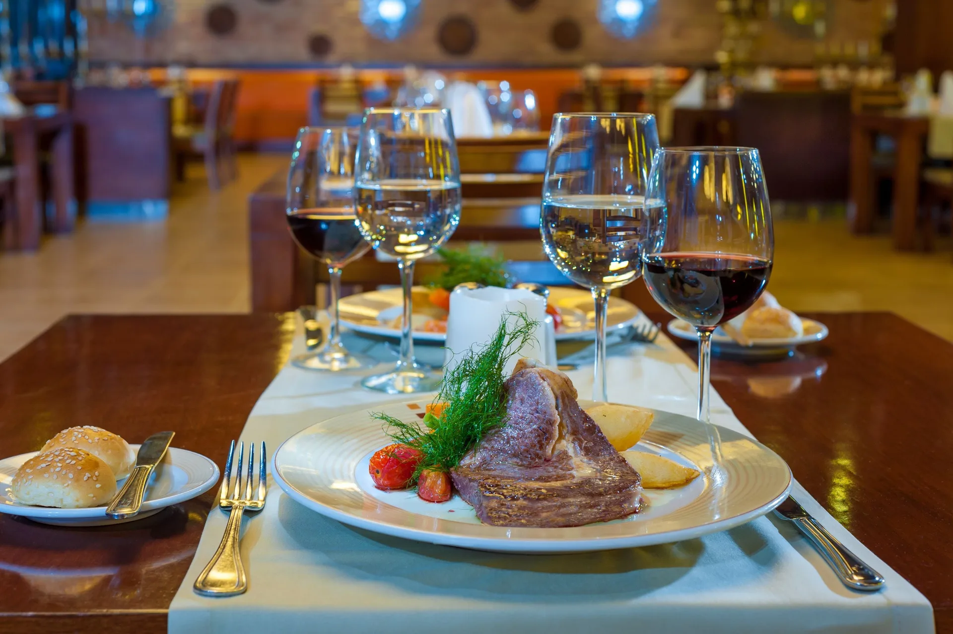 Plated steak dinner with wine glasses in a dining room at Grand Bavaro Princess.
