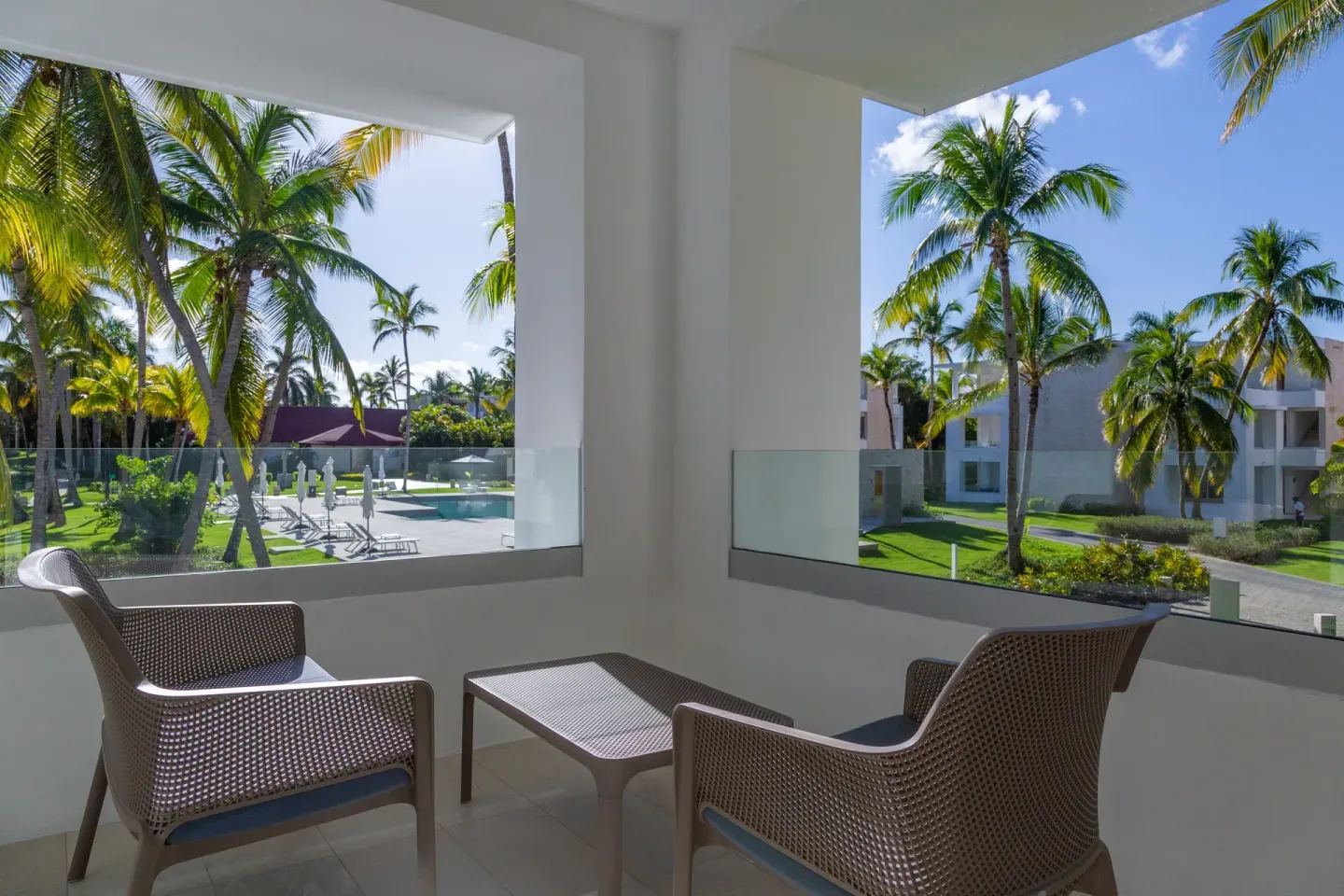 Bungalow balcony with two chairs and palm garden views at Grand Bavaro Princess.