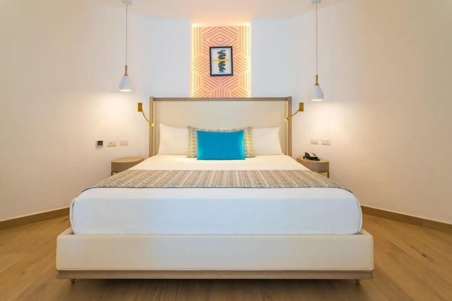Bungalow bedroom with a king bed and turquoise accent pillow at Grand Bavaro Princess.