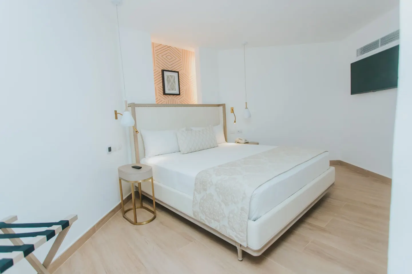 Bungalow king bed with pendant lights and luggage rack at Grand Bavaro Princess.