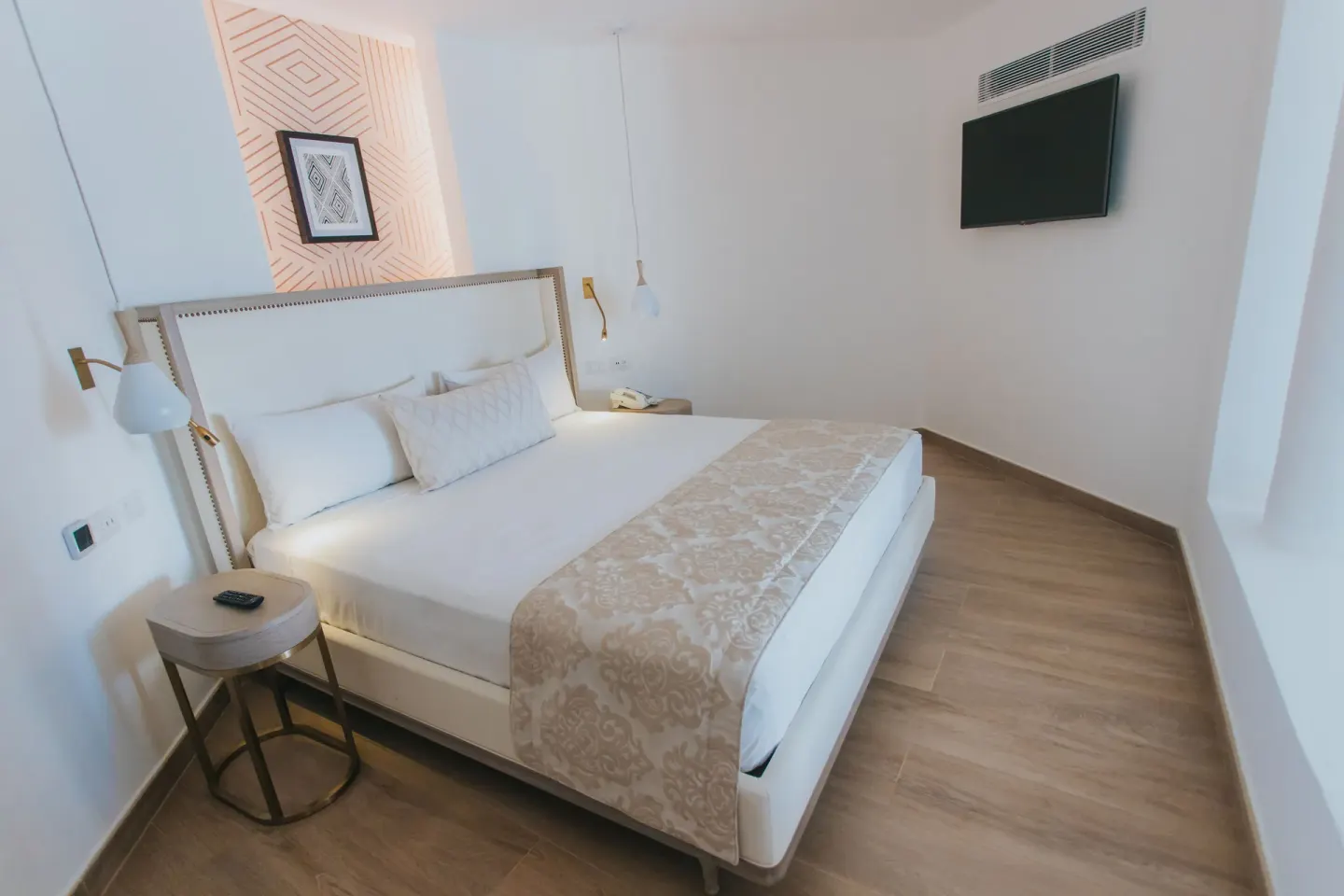 Bungalow king bed with wall-mounted TV at Grand Bavaro Princess.