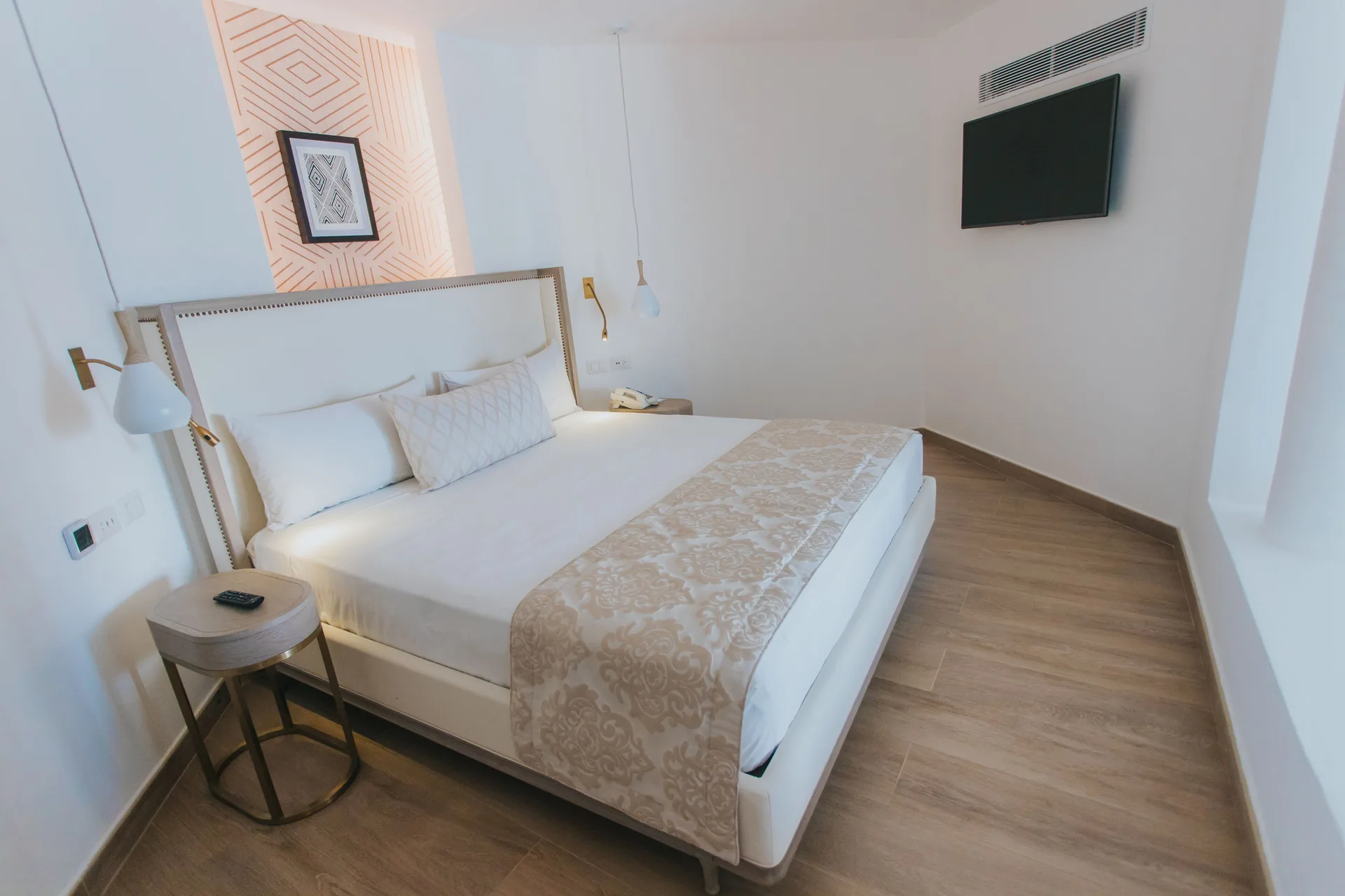 Bungalow king bed with wall-mounted TV at Grand Bavaro Princess.