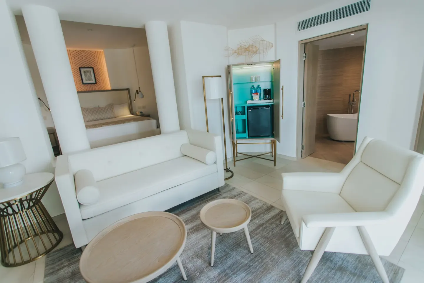 Bungalow living area with sofa, minibar cabinet, and bathroom doorway at Grand Bavaro Princess.