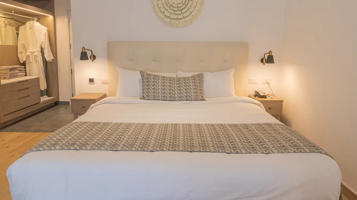 King bed with upholstered headboard and walk-in wardrobe in the Family Club Junior Suite at Grand Bavaro Princess.