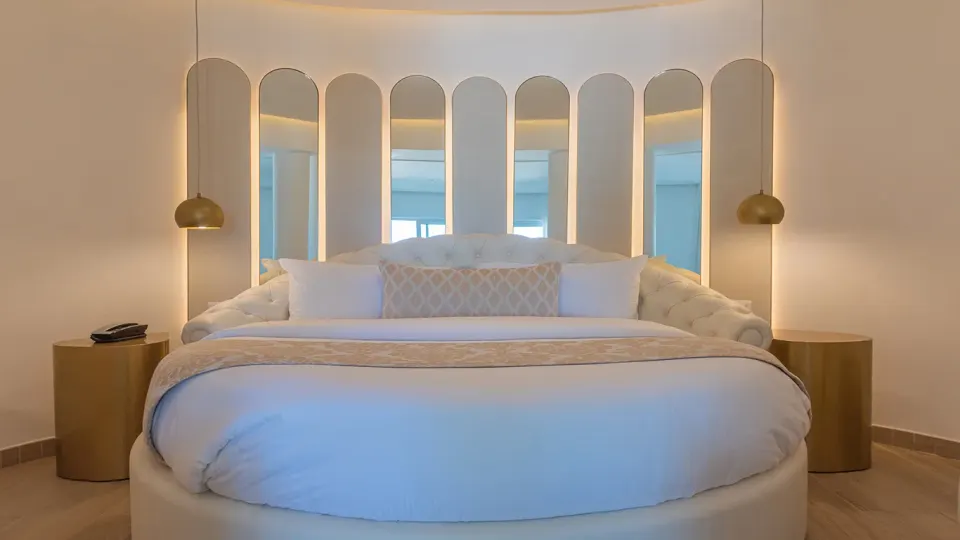 Signature round king bed with backlit arched headboard in the Honeymoon Platinum Suite at Grand Bavaro Princess.